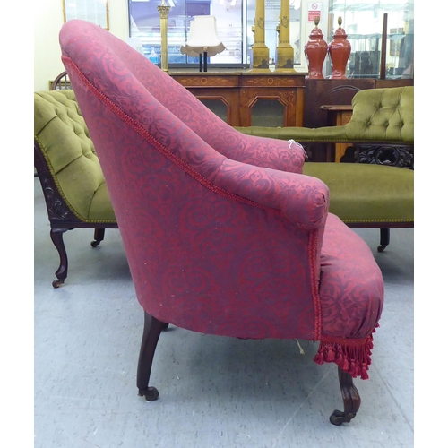 169 - An Edwardian tub style boudoir chair, upholstered in floral patterned maroon fabric with a fringed v... 