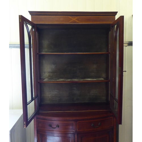 17 - An Edwardian crossbanded and ebony inlaid cabinet bookcase, the upper section with two glazed doors,... 