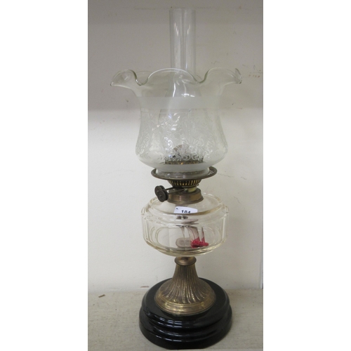 184 - A late Victorian clear glass oil lamp with a brass column and a black china plinth  19