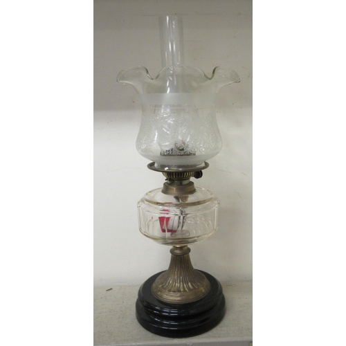 184 - A late Victorian clear glass oil lamp with a brass column and a black china plinth  19