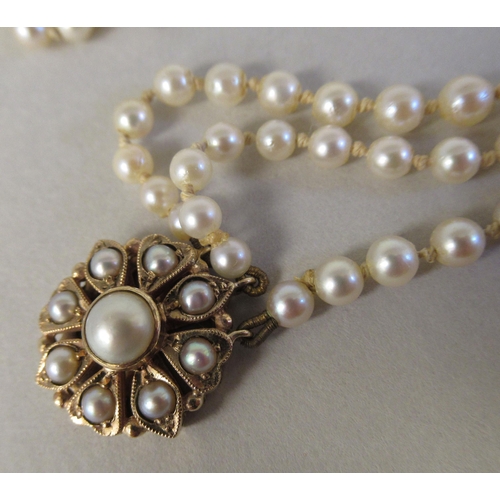 22 - A graduated three row pearl necklace, on a 9ct gold rosette clasp