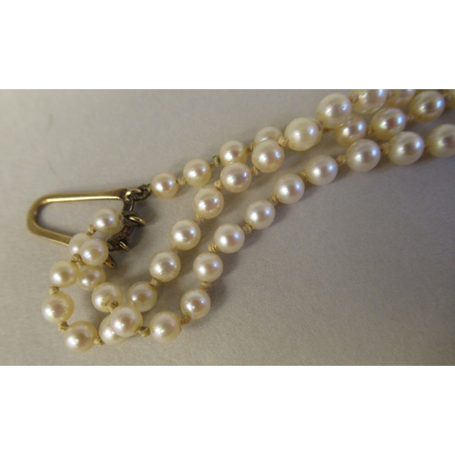 22 - A graduated three row pearl necklace, on a 9ct gold rosette clasp