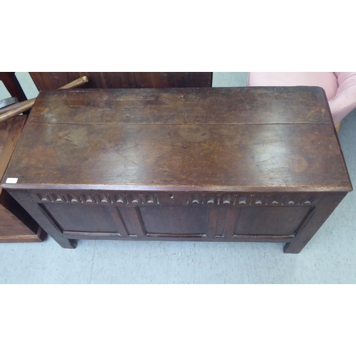 57 - A late 18thC tri-panelled oak chest with incised carved and moulded rails and a planked, hinged lid,... 