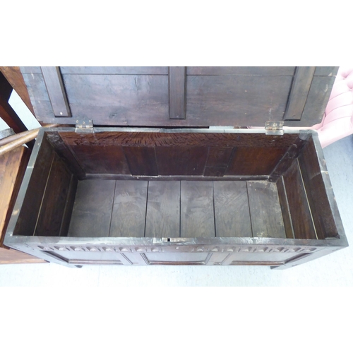 57 - A late 18thC tri-panelled oak chest with incised carved and moulded rails and a planked, hinged lid,... 