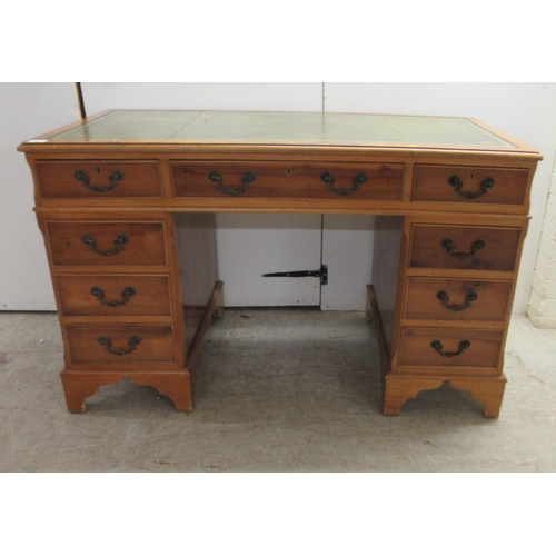 62 - A modern yewwood finished nine drawer twin pedestal desk with a tooled and gilded green hide scriber... 