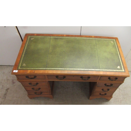 62 - A modern yewwood finished nine drawer twin pedestal desk with a tooled and gilded green hide scriber... 