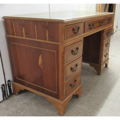 62 - A modern yewwood finished nine drawer twin pedestal desk with a tooled and gilded green hide scriber... 