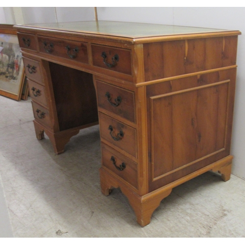 62 - A modern yewwood finished nine drawer twin pedestal desk with a tooled and gilded green hide scriber... 