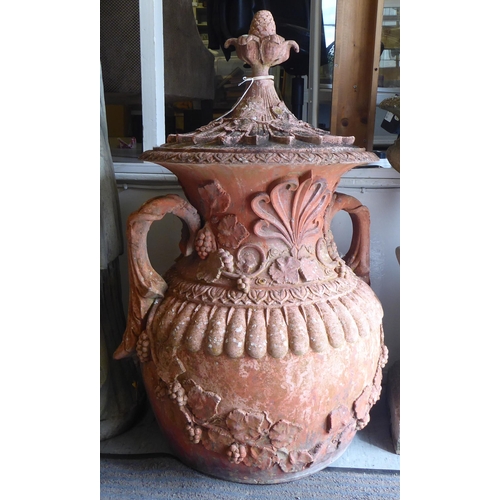 65 - A terracotta terrace vase of bulbous form with twin handles and cover, pineapple finials, moulded fo... 