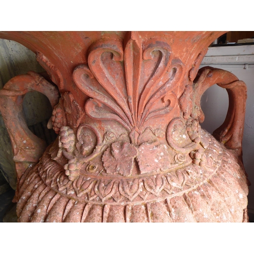 65 - A terracotta terrace vase of bulbous form with twin handles and cover, pineapple finials, moulded fo... 