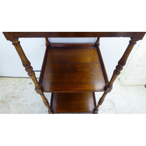 92 - An early 20thC oak three tier whatnot, on slender baluster supports, turned feet and cup casters  36... 