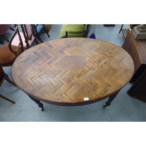 118 - A late 19thC Continental cherrywood oval dining table with a hardwood parquet finished top, over a d... 