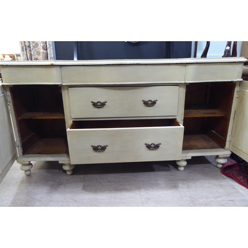 48 - An early 20thC washed green painted pine serpentine front sideboard with three frieze drawers, over ... 