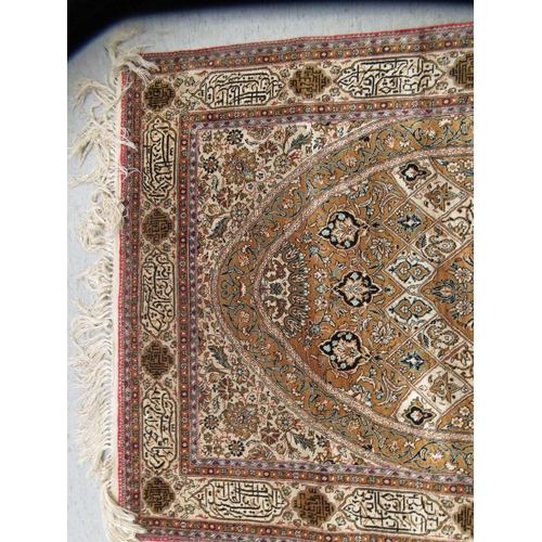 A Persian silk rug with dence floral decoration and a border of Arabic ...