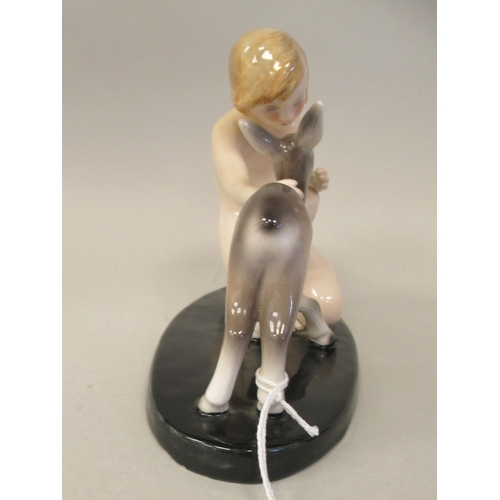 128 - An Art Deco Goldscheider, Claire Weiss porcelain group, a girl kneeling with a fawn, on an oval base... 