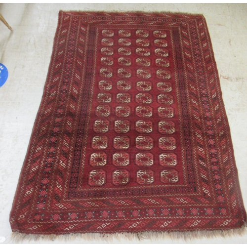 2 - A Bokhara rug, decorated with four columns of twelve octagonal guls, bordered by repeating diamond f... 