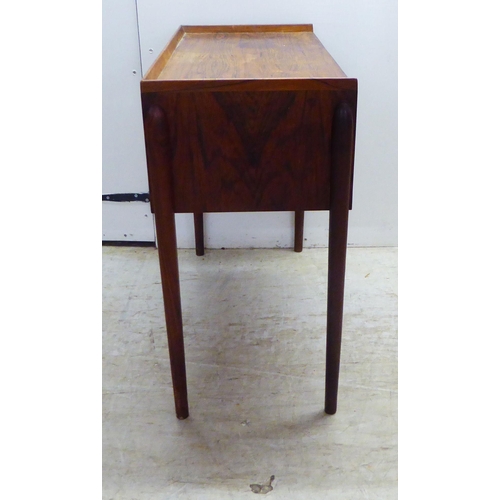 28 - A 1960s Danish rosewood side table with a low galleried top, over two enclosed shallow shelves, rais... 