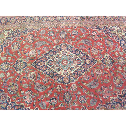 50 - A Kashan carpet, decorated with a central diamond shaped motif, profusely bordered by floral and fol... 