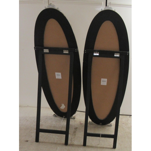 66 - A pair of Victorian style oval dressing mirrors, set in ornately moulded gilt frames, on folding eas... 