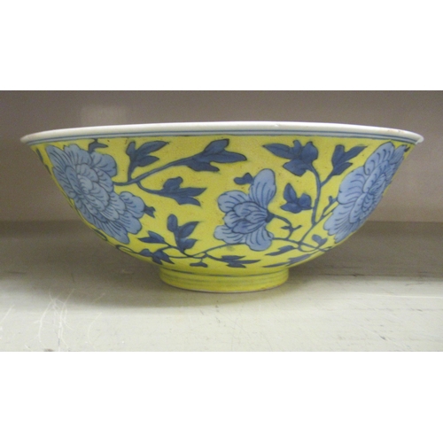 127 - A 19thC Chinese porcelain footed bowl, decorated with blue flowers and foliage, on a yellow ground  ... 