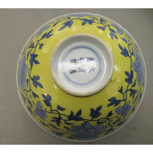 127 - A 19thC Chinese porcelain footed bowl, decorated with blue flowers and foliage, on a yellow ground  ... 