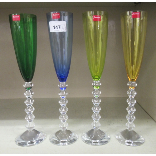 147 - A set of four coloured Baccarat Crystal presentation pedestal wine flutes  each bearing a label  cas... 