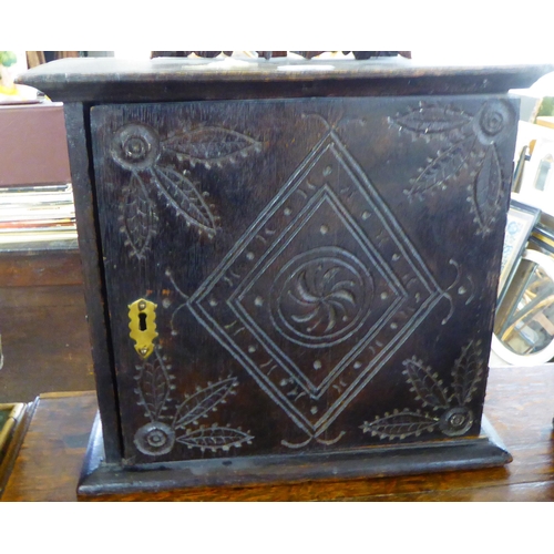 183 - A mid 18thC oak wall cabinet, surmounted by two carved masks, over a door, enclosing five drawers&nb... 