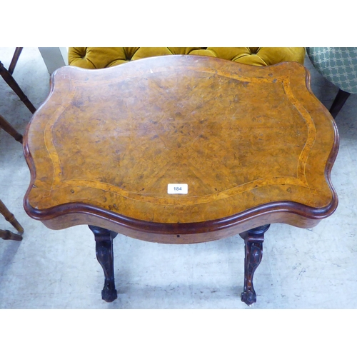 184 - A late Victorian walnut serpentine front sewing table, the hinged lid enclosing a fitted interior, r... 