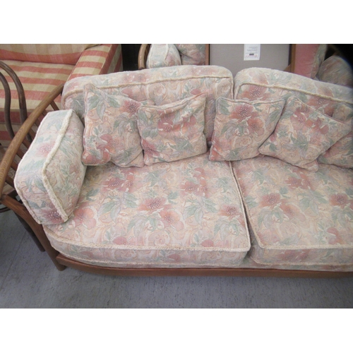 192 - A modern Ercol Renaissance elm and oak framed three person settee with floral patterned cushions