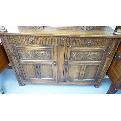 229 - An early 20thC oak court cupboard with an angular middle section and opposing pillars, over two frie... 