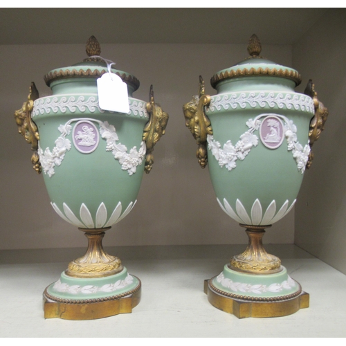 24 - A pair of Wedgwood green Jasperware and gilt metal mounted pedestal urn and cover, decorated with fr... 