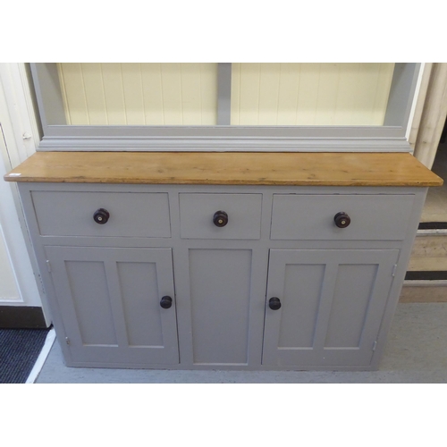 76 - An early 20thC later painted grey, pine kitchen dresser, the upper section comprising three open she... 