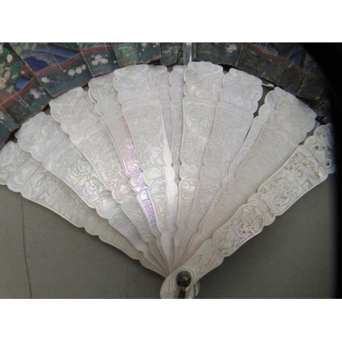 95 - An early 20thC engraved mother-of-pearl and painted paper fan, featuring standing figures  the guard... 