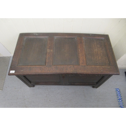 230 - An early 19thC panelled oak coffer with straight sides and a hinged lid, raised on block feet  ... 