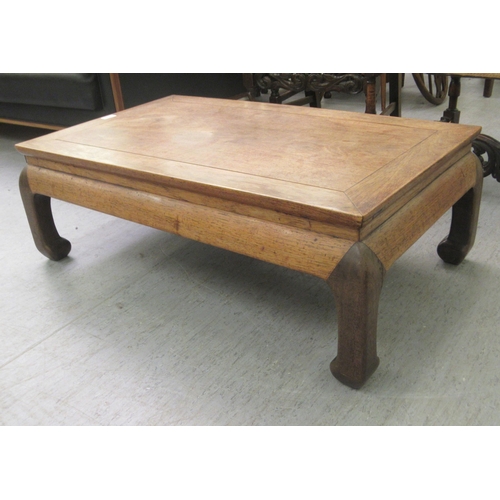 17 - An early 20thC Chinese fruitwood Kang table, the top with a mitred edge, raised on curved legs  12.5... 