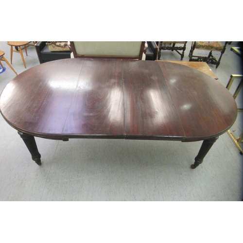 214 - A late Victorian mahogany wind-out dining table, raised on tapered, reeded legs and brass sabots and... 