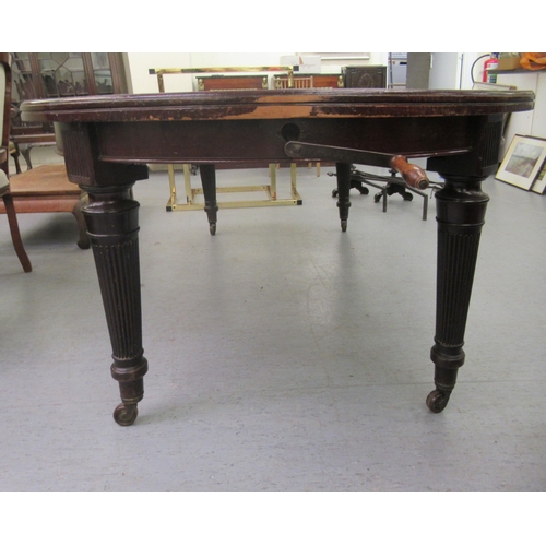 214 - A late Victorian mahogany wind-out dining table, raised on tapered, reeded legs and brass sabots and... 