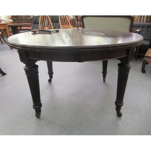 214 - A late Victorian mahogany wind-out dining table, raised on tapered, reeded legs and brass sabots and... 