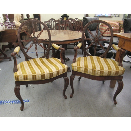 264 - A pair of late 19thC Continental walnut framed chairs, each with a circular wheelback, swept open ar... 