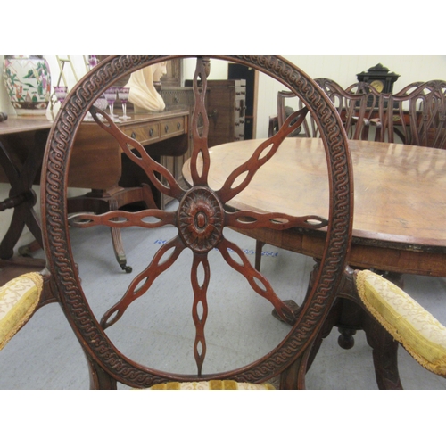 264 - A pair of late 19thC Continental walnut framed chairs, each with a circular wheelback, swept open ar... 