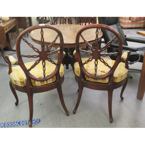 264 - A pair of late 19thC Continental walnut framed chairs, each with a circular wheelback, swept open ar... 