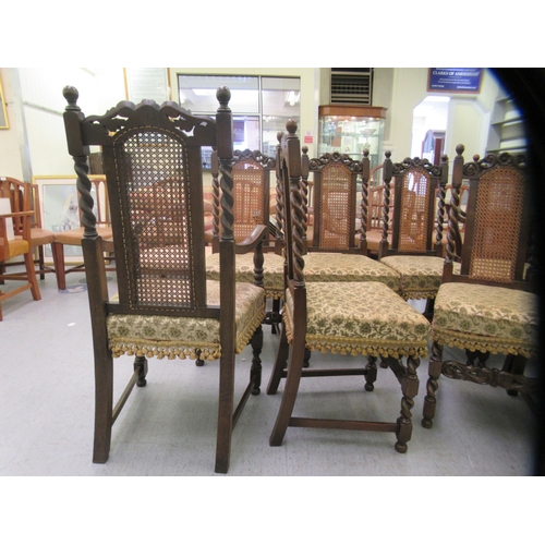 272 - A set of ten 1920s/1930s Carolean style oak framed dining chairs, each with a rosette carved crest, ... 