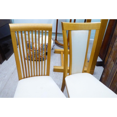 48 - Two dissimilar pairs of light oak framed dining chairs 