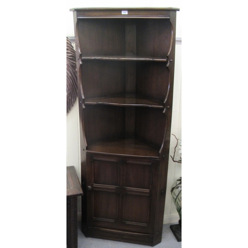 268 - An Ercol dark oak corner unit with three open shelves, over a base drawer, on a plinth  72