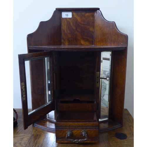 13 - A 1920s oak hanging smokers corner cabinet with a lockable, bevelled glazed panelled door and a base... 