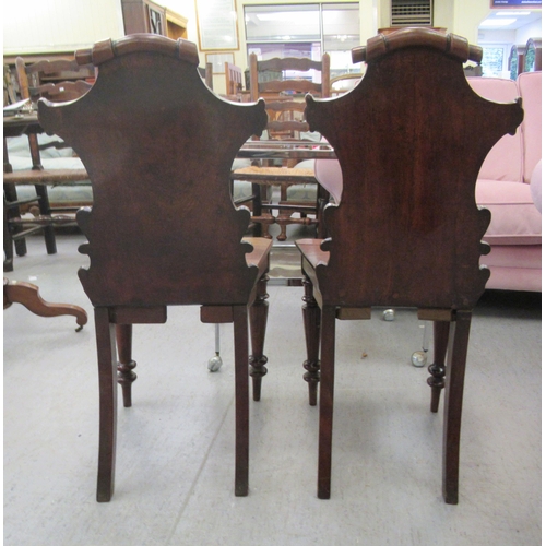 137 - A pair of late Victorian mahogany framed hall chairs with C-scroll carved solid backs and seats, rai... 