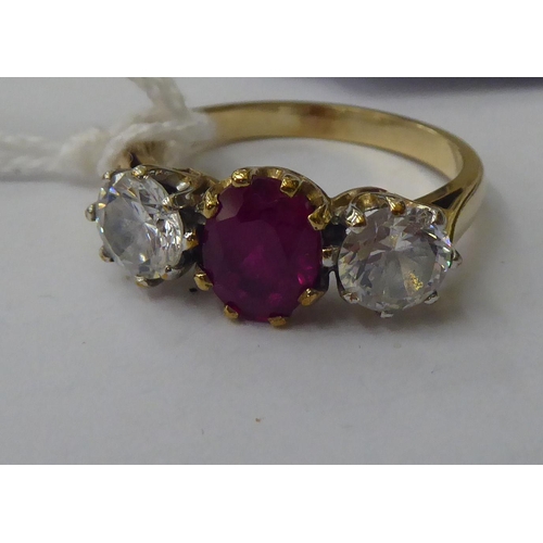 143 - A 9ct gold ring, claw set with a central bevelled ruby, flanked by a pair of cubic zirconia's