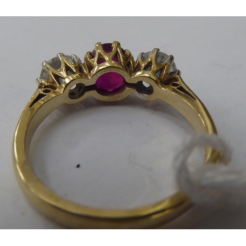 143 - A 9ct gold ring, claw set with a central bevelled ruby, flanked by a pair of cubic zirconia's