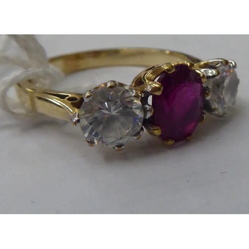 143 - A 9ct gold ring, claw set with a central bevelled ruby, flanked by a pair of cubic zirconia's