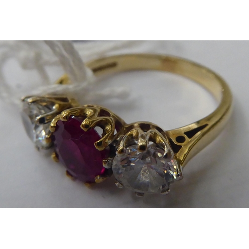 143 - A 9ct gold ring, claw set with a central bevelled ruby, flanked by a pair of cubic zirconia's